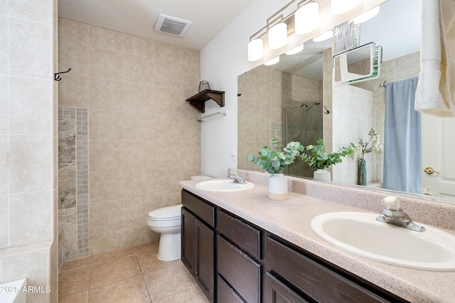 bathroom with tile patterned flooring, vanity, a tile shower, and toilet