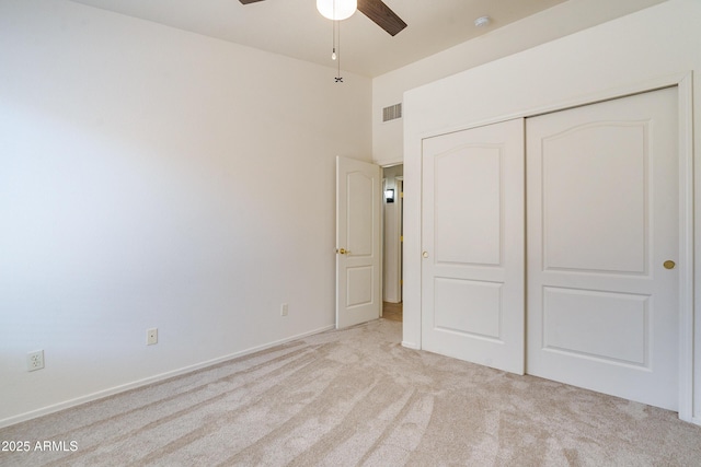 unfurnished bedroom featuring light colored carpet, a closet, and a high ceiling