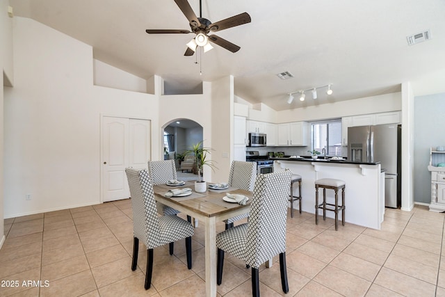 dining room featuring light tile patterned floors, vaulted ceiling, sink, and ceiling fan