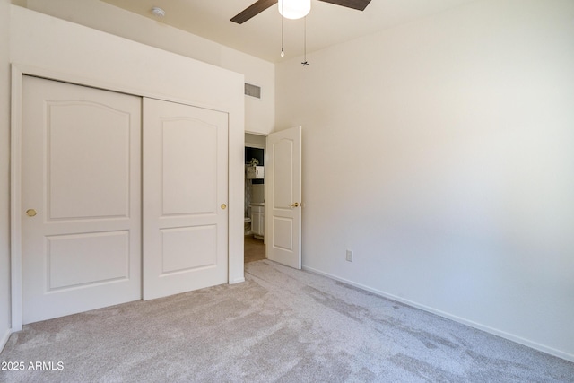 unfurnished bedroom featuring ceiling fan, light colored carpet, and a closet