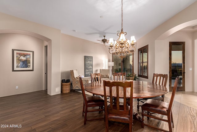 dining area with arched walkways, ceiling fan with notable chandelier, and wood finished floors