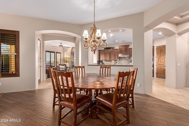 dining room featuring a ceiling fan, arched walkways, and light wood finished floors