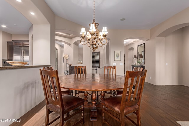 dining area with a chandelier, arched walkways, recessed lighting, and wood finished floors