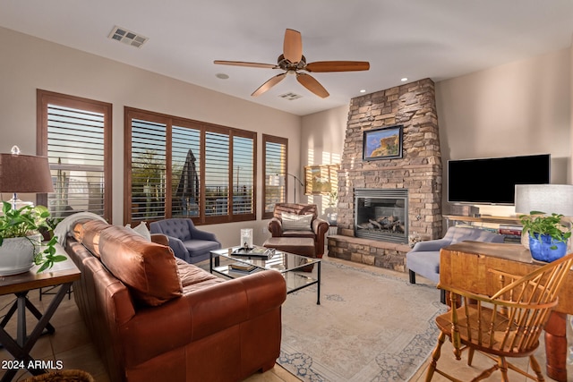 living room with ceiling fan, a stone fireplace, and tile patterned floors