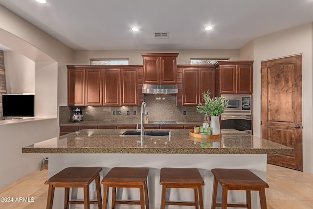 kitchen with visible vents, decorative backsplash, appliances with stainless steel finishes, a sink, and under cabinet range hood