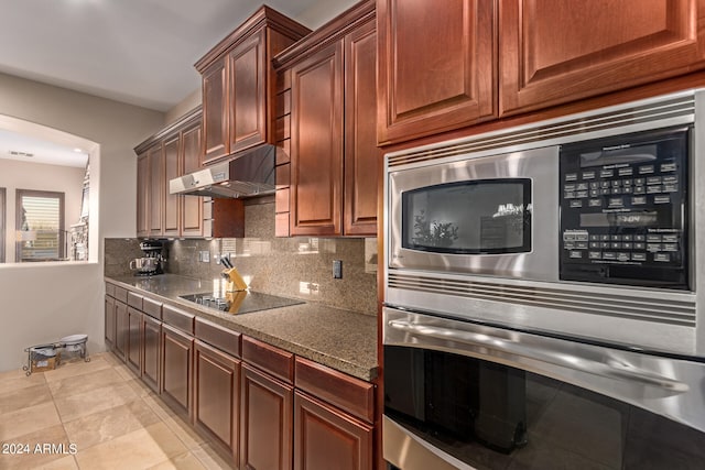 kitchen with appliances with stainless steel finishes, light tile patterned floors, and tasteful backsplash