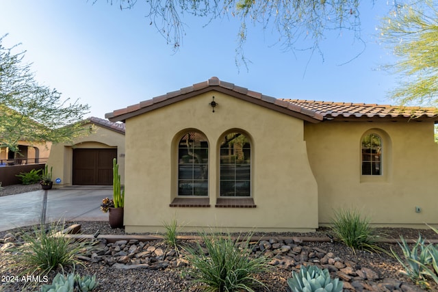 view of front of house featuring a garage, driveway, a tile roof, and stucco siding