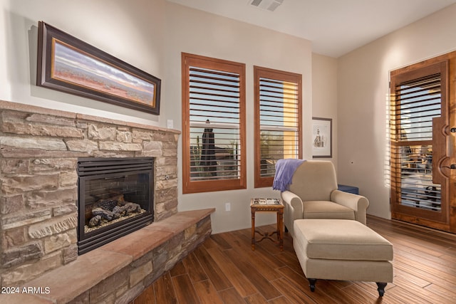 living area with a stone fireplace and hardwood / wood-style floors