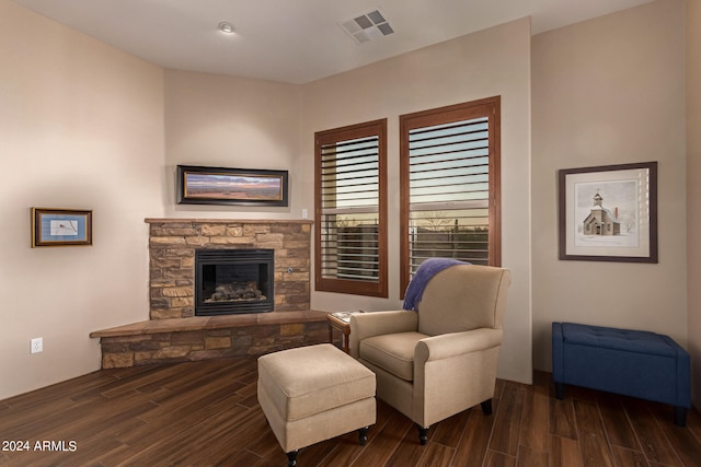 living area with a stone fireplace, wood finished floors, and visible vents