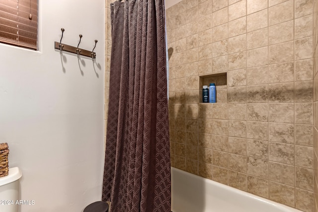 bathroom featuring toilet and shower / tub combo with curtain