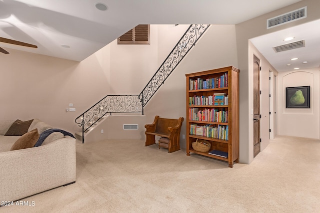 living area featuring light carpet and ceiling fan