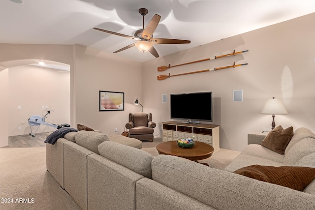 living area with light carpet, ceiling fan, and arched walkways