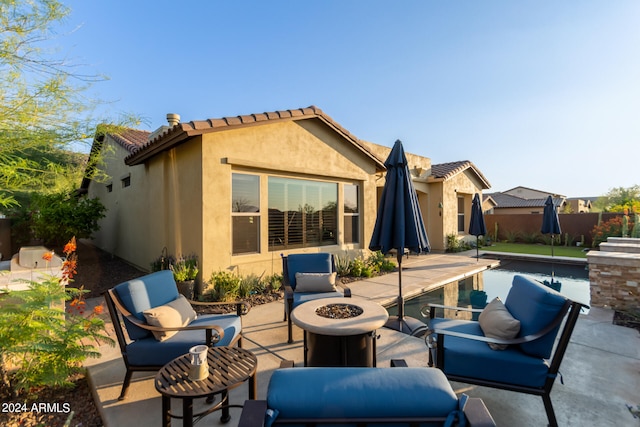 back of property with a fenced in pool, a patio area, and an outdoor fire pit