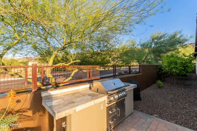 view of patio featuring fence, exterior kitchen, and area for grilling