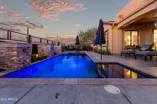 pool at dusk with a patio area and a fenced in pool