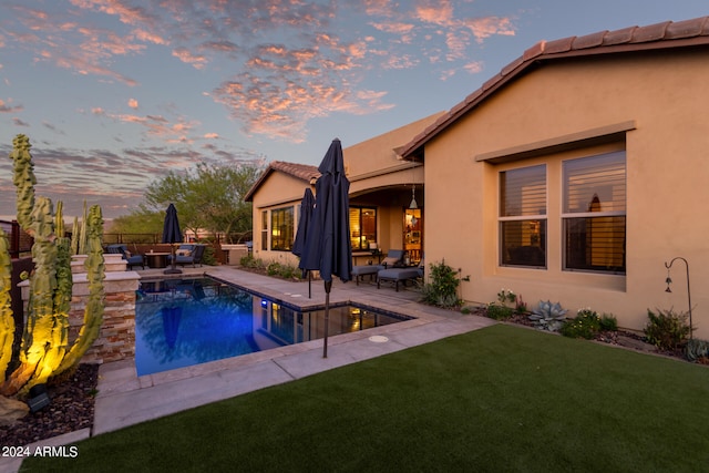 pool at dusk with a yard, an outdoor living space, and a patio area