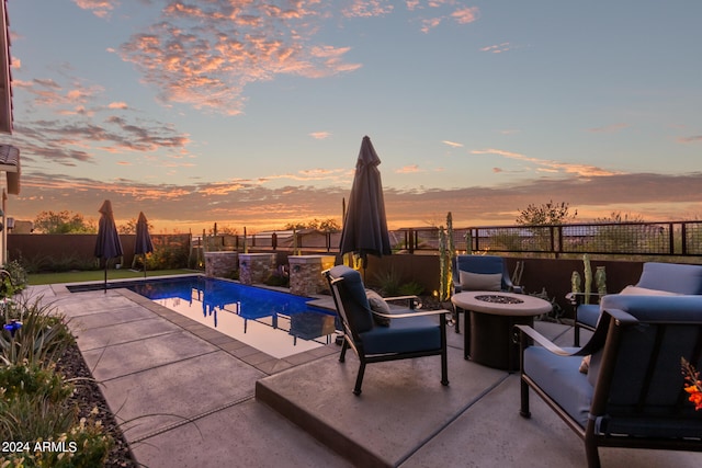 pool at dusk featuring a patio and an outdoor fire pit