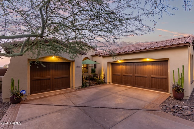 view of front facade featuring driveway, a tile roof, a garage, and stucco siding