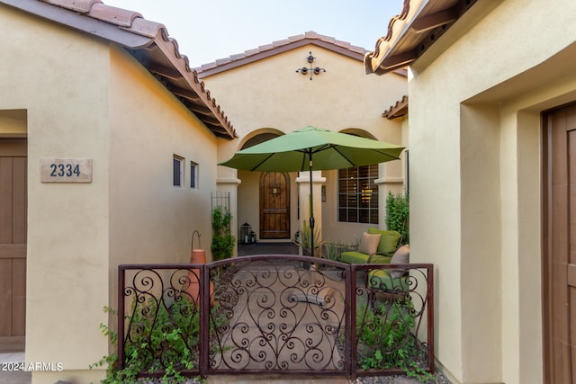 property entrance featuring a tiled roof, a gate, and stucco siding