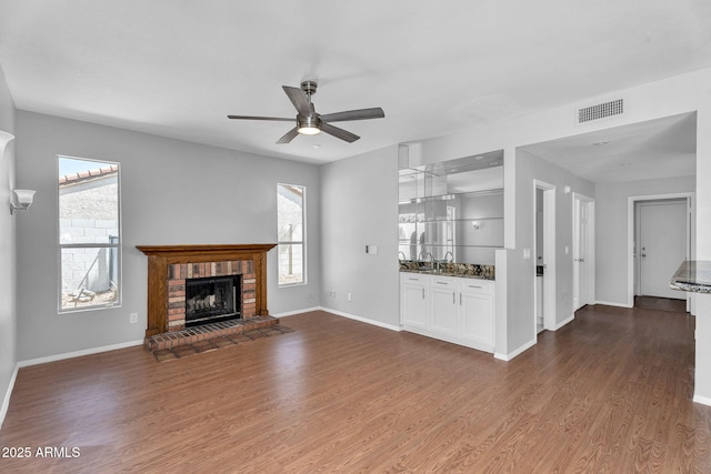 unfurnished living room featuring a ceiling fan, visible vents, plenty of natural light, and dark wood finished floors