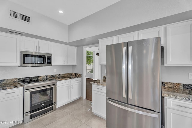 kitchen featuring stainless steel appliances, dark stone countertops, white cabinetry, and visible vents