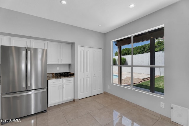 kitchen featuring light tile patterned floors, white cabinets, freestanding refrigerator, dark stone counters, and recessed lighting