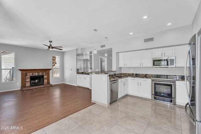 kitchen featuring ceiling fan, stainless steel appliances, open floor plan, a peninsula, and visible vents