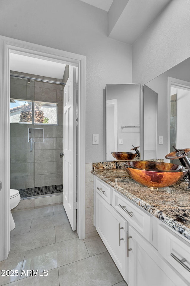 full bathroom with vanity, tile patterned floors, a shower stall, and toilet