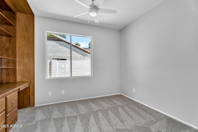 carpeted empty room featuring ceiling fan and baseboards