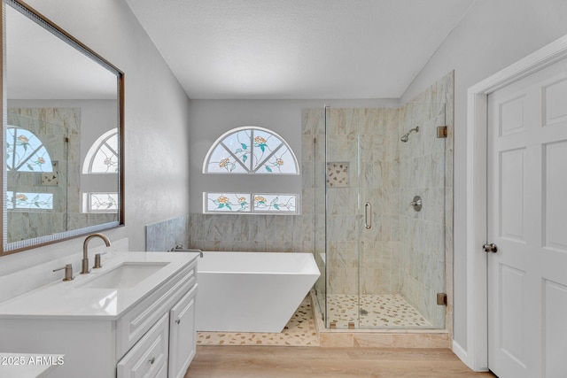 full bathroom featuring vanity, a freestanding tub, a stall shower, and wood finished floors
