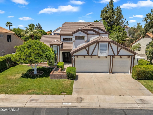 english style home featuring a tiled roof, driveway, a garage, a front lawn, and stucco siding