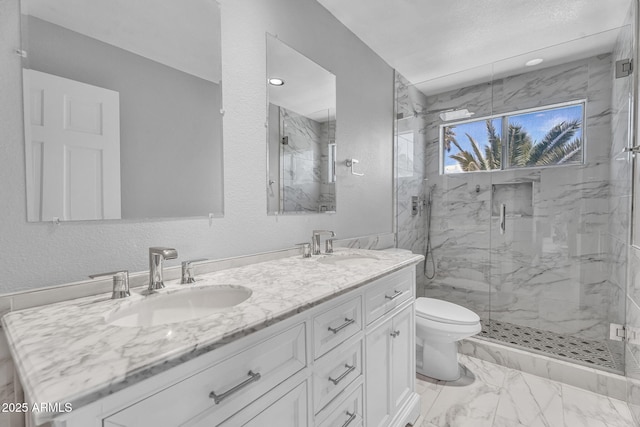 bathroom featuring a sink, a marble finish shower, toilet, and double vanity