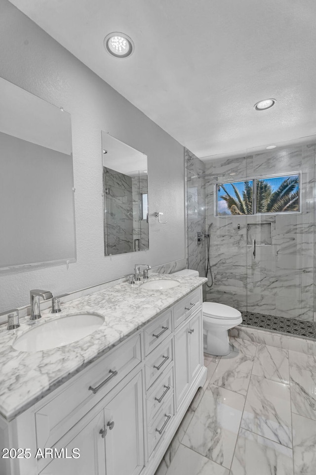 full bath with a sink, a marble finish shower, toilet, and double vanity