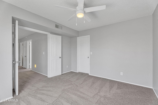 unfurnished bedroom featuring carpet flooring, a textured ceiling, visible vents, and baseboards