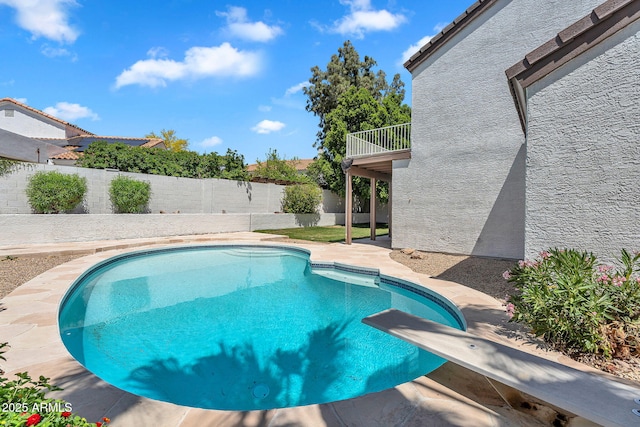 view of swimming pool with a fenced backyard, a fenced in pool, a diving board, and a patio