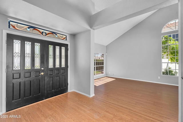 foyer entrance with baseboards, high vaulted ceiling, and wood finished floors