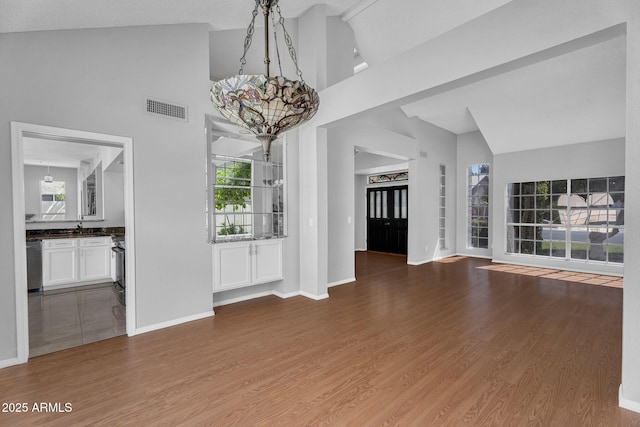 unfurnished dining area with visible vents, plenty of natural light, wood finished floors, and a notable chandelier