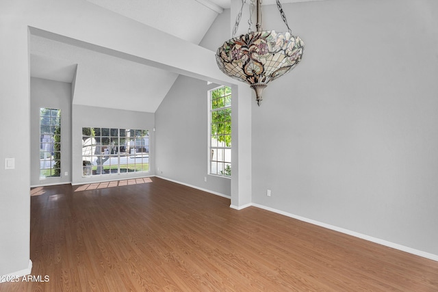 interior space with baseboards, a notable chandelier, wood finished floors, and vaulted ceiling