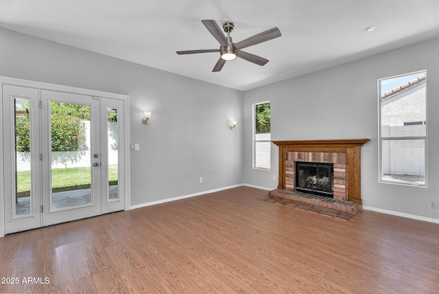 unfurnished living room featuring a ceiling fan, baseboards, wood finished floors, and a fireplace