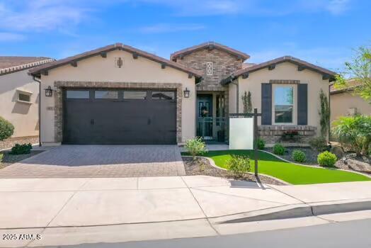 mediterranean / spanish-style home featuring an attached garage, driveway, and stucco siding