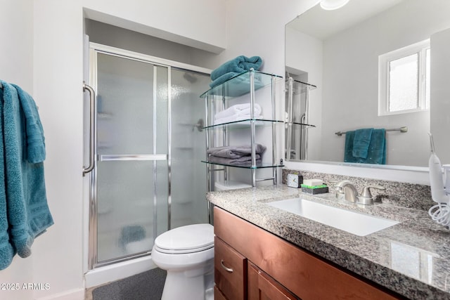 bathroom featuring vanity, a shower with door, and toilet