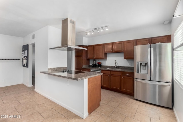 kitchen with sink, dark stone countertops, stainless steel appliances, island range hood, and kitchen peninsula