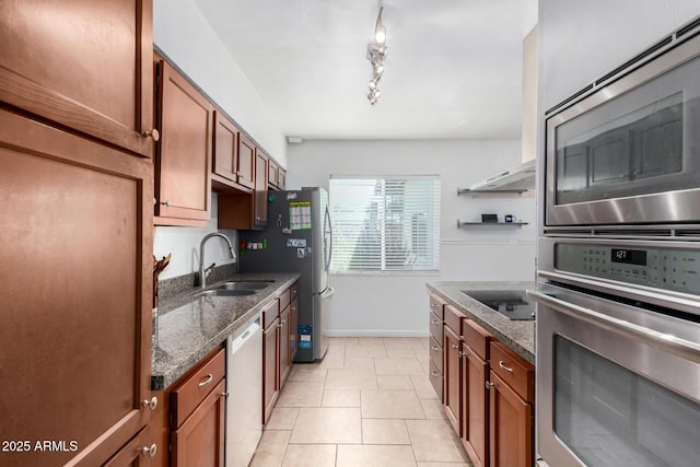 kitchen featuring dark stone countertops, sink, light tile patterned flooring, and appliances with stainless steel finishes