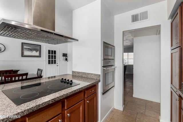 kitchen with appliances with stainless steel finishes, ventilation hood, and light tile patterned floors