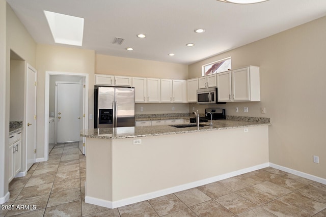 20007 N Siesta Rock Dr, Surprise, AZ 85374 - kitchen with stainless steel appliances, a sink, a peninsula, light stone counters, and white cabinets