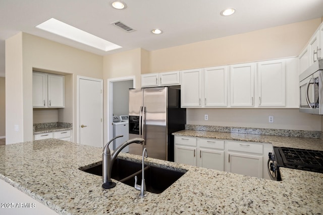 20007 N Siesta Rock Dr, Surprise, AZ 85374 - kitchen featuring appliances with stainless steel finishes, a sink, independent washer and dryer, light stone countertops, and white cabinets