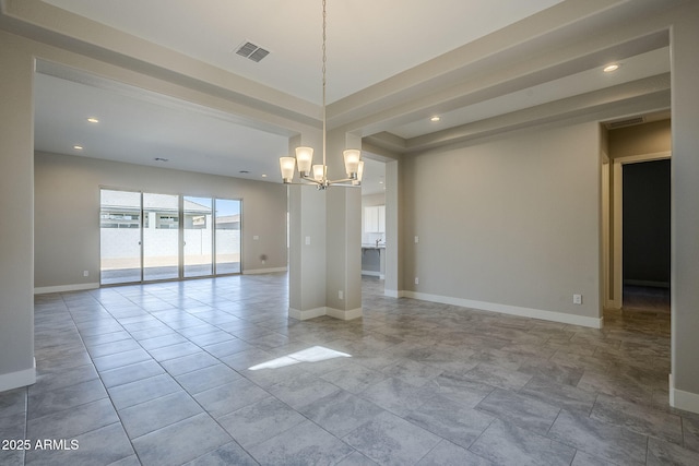 empty room featuring a notable chandelier and a raised ceiling