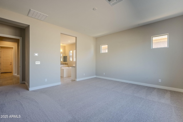 unfurnished bedroom with ensuite bath, light carpet, and multiple windows