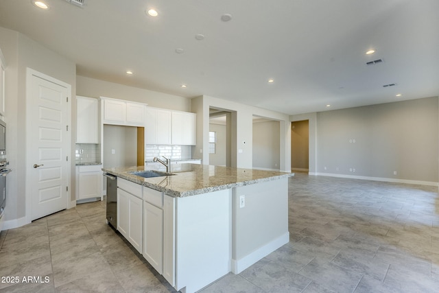 kitchen with sink, white cabinetry, stainless steel dishwasher, light stone countertops, and a kitchen island with sink