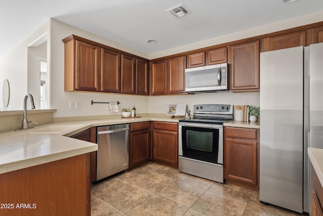973 E Kelsi Ave, San Tan Valley, AZ 85140 - kitchen featuring stainless steel appliances, a sink, light countertops, light tile patterned flooring, and brown cabinetry